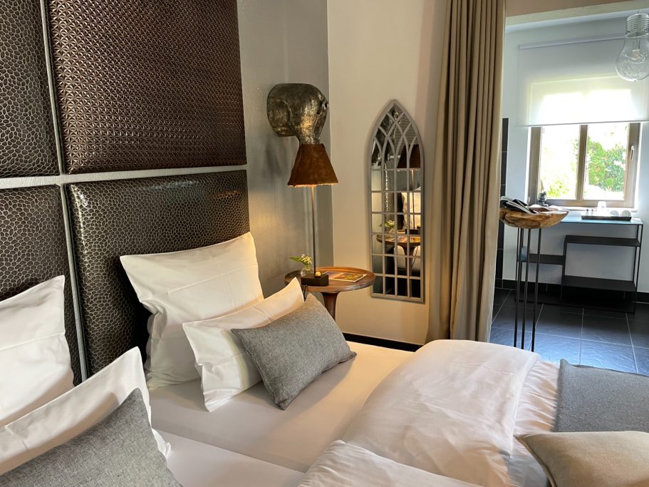 Helles Schlafzimmer mit einem großen Bett, Kissen und einem Fenster im Hintergrund.