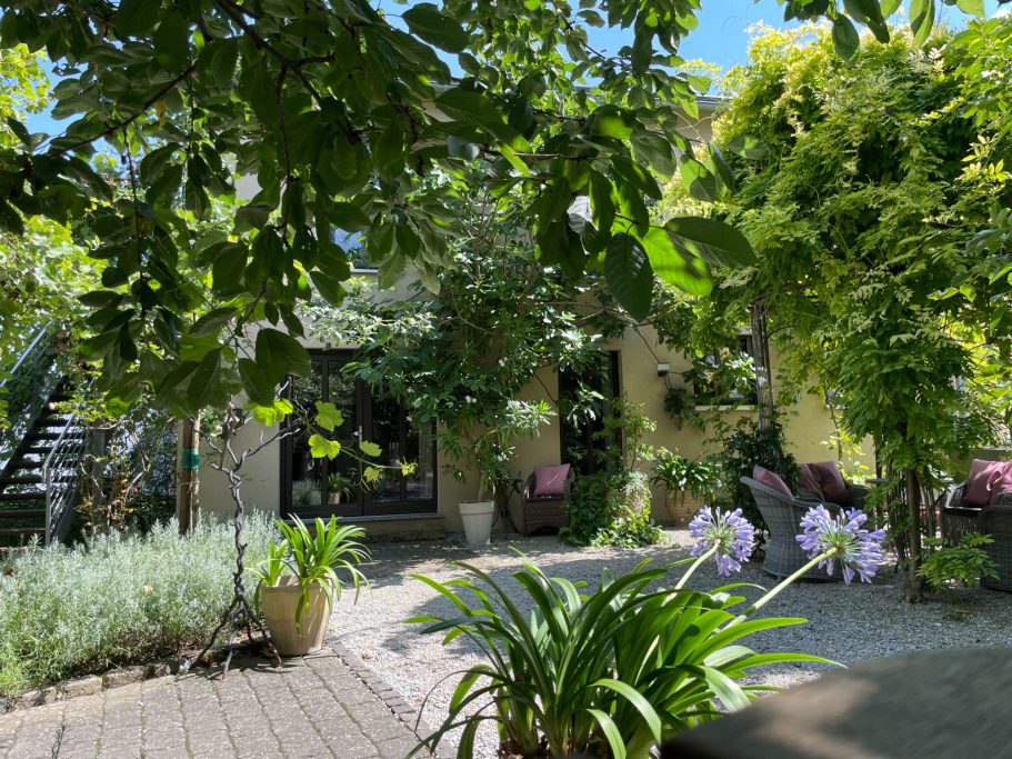 Ein grüner Garten mit Blumen, Pflanzen und einem gemütlichen Sitzbereich.