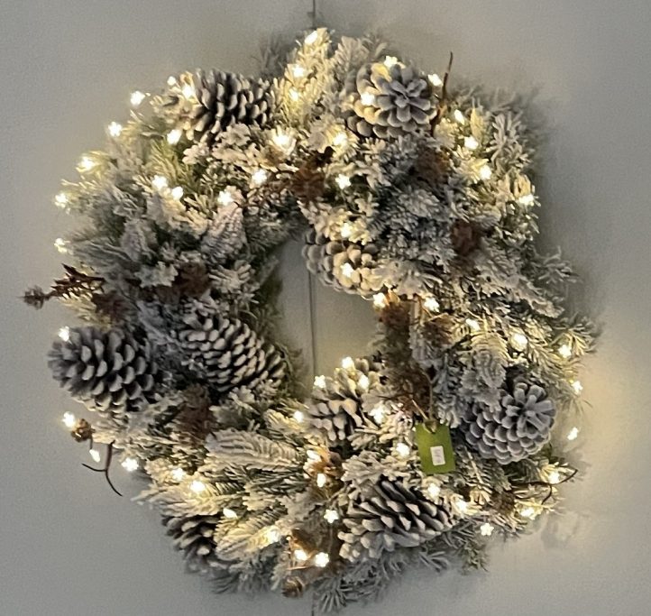 Frostiger Kranz mit Tannenzapfen und Lichtern, dekorativ für die Winterzeit.