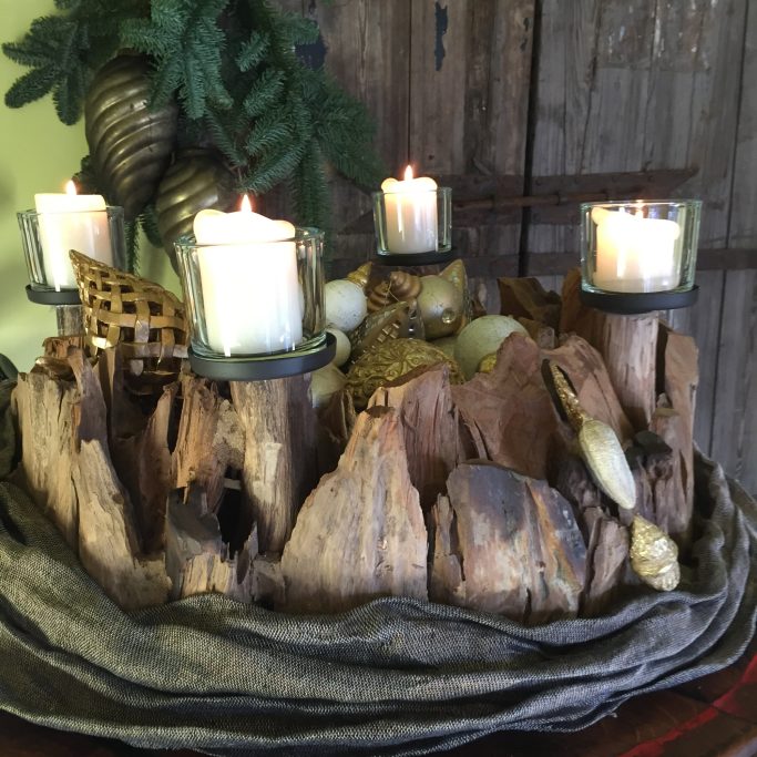 Dekoratives Arrangement aus Holzstücken mit Kerzen und Naturmaterialien.