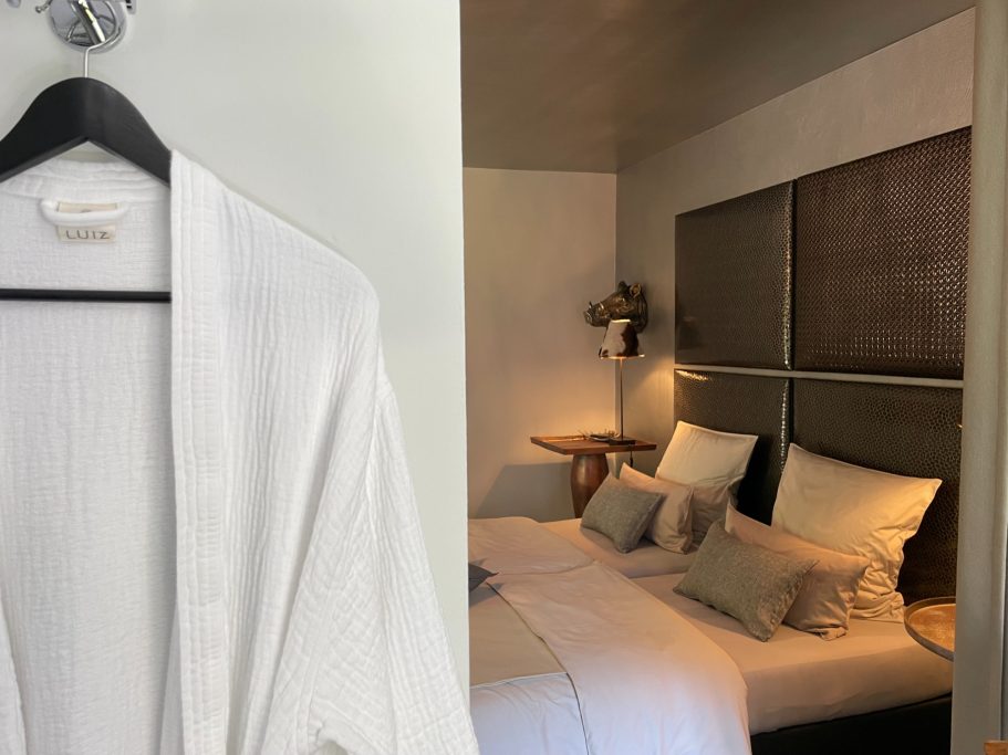 Bademantel hängt an der Wand, Blick auf ein elegantes Schlafzimmer mit Doppelbett.